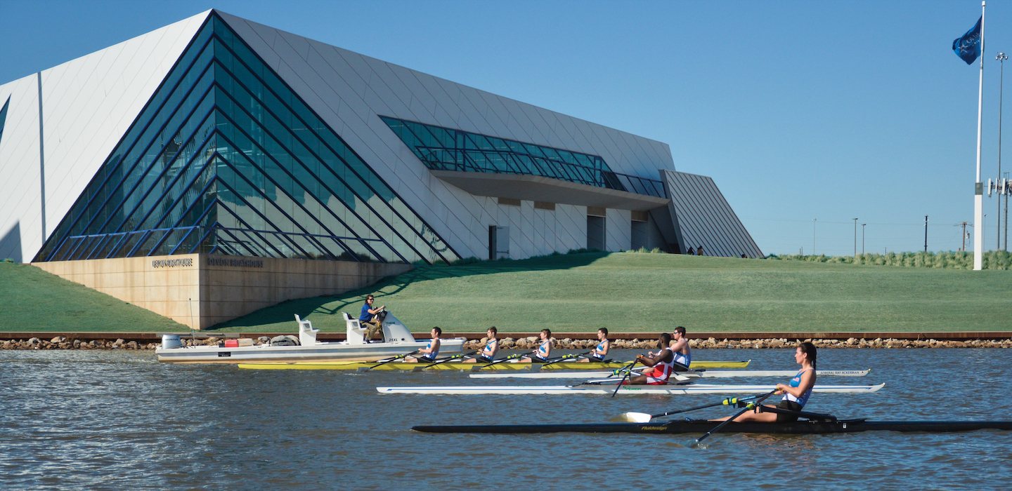 Image of USRowing National High Performance Center athletes rowing on the Oklahoma River, in front of the Devon Boathouse