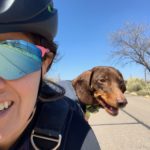 Woman Riding with a dachshund dog in a backpack.
